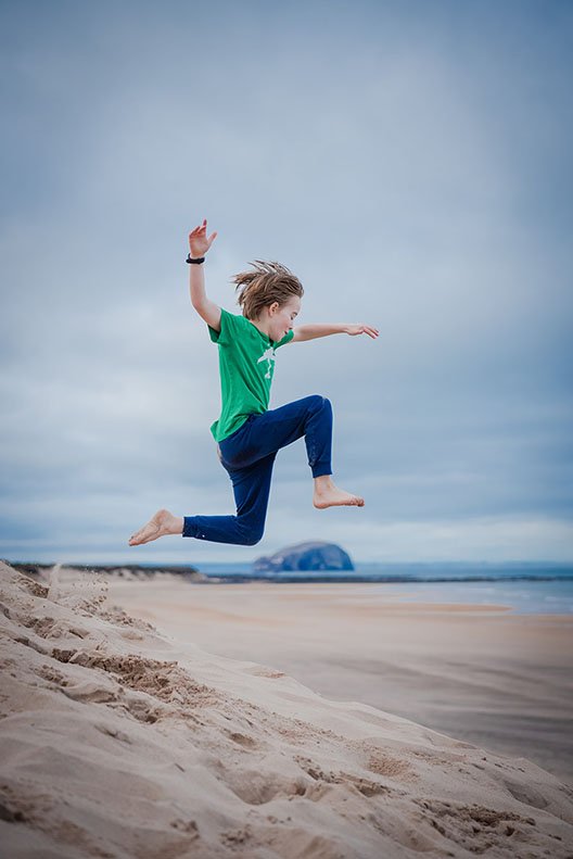 A child leaping above the beach