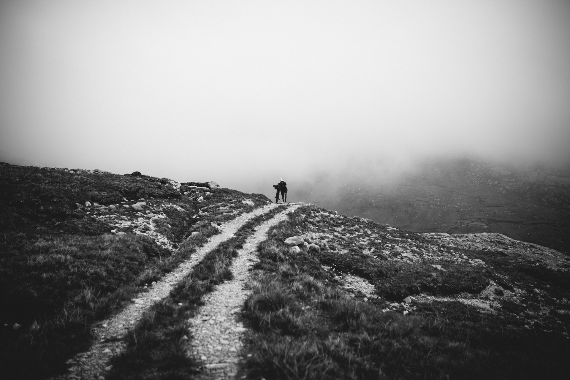 A cyclist climbing into mountain mist