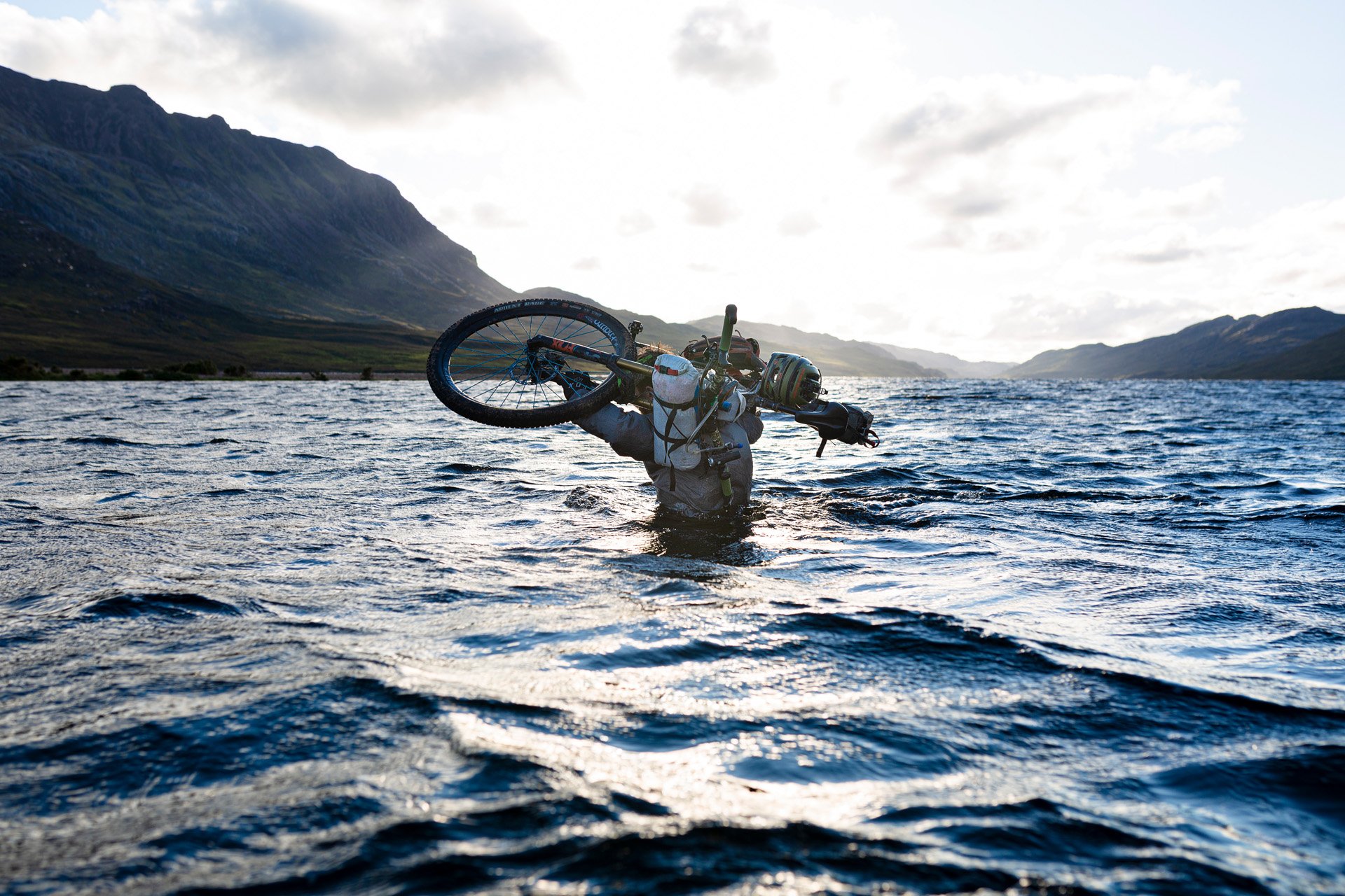 Someone carrying a bicycle through deep water